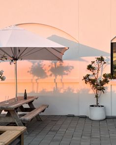 an outdoor table with umbrellas and potted plants on the side of a building