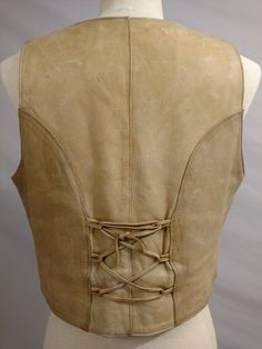 "Fabulous artisan made natural leather vest. Laced on the back. The style is classic and flattering. A wonderful layering piece. Condition is good, light markings, one scrape. Even wear and surface 'dirt', no stains. Label is Walter Leather Company Steve Gamino Collection Made in Puerto Vallarta Mexico. Leather is thick and soft, nice look, feel, and thickness. Same leather front and back. Plaid lining. Six silver buttons in front, no pockets. Well made, quality construction. Unisex potential. S Fitted Leather Festival Vest, Leather Sleeveless Vest For Festivals, Classic Sleeveless Leather Vest, Classic Fitted Leather Vest, Fitted Western Leather Vest, Fitted Beige Bohemian Vest, Bohemian Fitted Beige Vest, Fitted Bohemian Beige Vest, Vintage Fitted Leather Vest