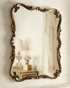 a mirror sitting on top of a wall next to a table with a lamp in it