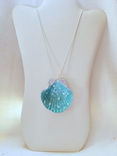 This is a painted shell necklace with  sea shaped appliques onto a resin foundation. Ocean-inspired Turquoise Shell Jewelry, Blue Shell-shaped Ocean-inspired Necklace, Ocean-inspired Turquoise Pendant Necklace, Ocean-inspired Blue Shell-shaped Necklace, Blue Ocean-inspired Shell-shaped Necklace, Turquoise Shell-shaped Necklace For Gift, Turquoise Shell Necklace For Gift, Turquoise Ocean-inspired Shell Necklace, Ocean-inspired Blue Shell Jewelry