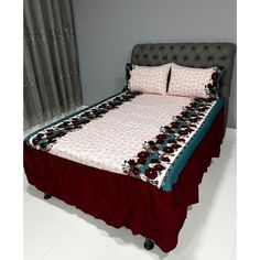 a bed with two pillows on top of it and a red blanket over the headboard