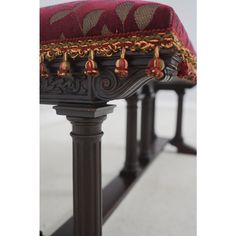 an ornately decorated bench with red and gold trimmings on the seat cushion