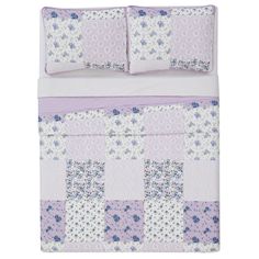 a purple and white quilted bed with blue flowers on the pillowcase, along with two matching pillows