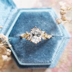 an engagement ring sitting on top of a blue velvet box