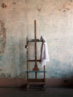 an old wooden shelf with a towel on it in front of a wall that has peeling paint