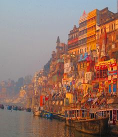 boats are docked in the water next to some buildings on the side of a hill