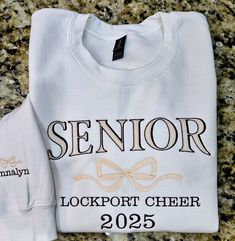 SENIOR 2025 Sweatshirt with bow, Trendy high school senior Sweatshirt, Embroidered Sweatshirt, Cute Sweatshirt, For Her. Great Senior night team shirts.  Message for bulk orders.  be sure you are ordering the option you want. There are T-shirts, Crewnecks or Hoodies. Bow and name on the cuff is an optional add on for sweatshirts or hoodies ONLY. **  Choose the size with +cuff to add the sleeve design to your order.  We offer a variety of custom made embroidered shirts.  See photos above for sizing.  The primary color is the shirt color.  Visit the rest of our shop at KikiLeeOriginals.etsy.com  Thank you for visiting! Unisex sizes. Available in crewneck or hoodie or t-shirts. 99% of the shirts are Gildan brand heavy weight cotton/polyester.  Occasionally an equivalent brand will be used. White Embroidered T-shirt For College, Game Day White Sweatshirt With Embroidered Graphics, White Team Spirit Sweatshirt With Embroidered Graphics, White Game Day Sweatshirt With Embroidered Graphics, White Sweatshirt With Embroidered Graphics For Team Spirit, White Crew Neck T-shirt For College, White Embroidered Graphics T-shirt For College, White Sporty Sweatshirt With Letter Embroidery, Sporty White Sweatshirt With Letter Embroidery