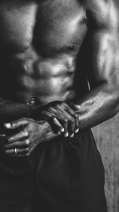 a shirtless man with his hands on his chest, posing for a black and white photo