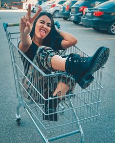 a woman sitting in a shopping cart making the peace sign with her hands and legs