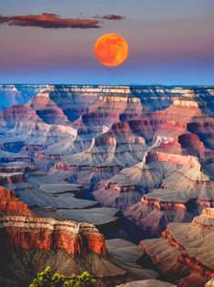 the full moon is setting over the grand canyons in the desert, with an orange hue