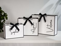 three black and white gift bags with bows on the front, one for someone's special day