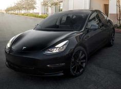 a black tesla parked in front of a building