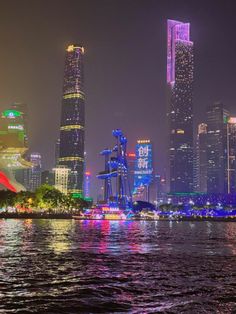 the city skyline is lit up at night with bright lights and skyscrapers in the background