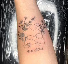 a woman's arm with a tattoo on it that has flowers and leaves in the shape of a dog