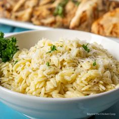 a white bowl filled with rice and parsley on top of a blue tablecloth