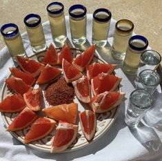 a plate filled with sliced up grapefruits next to glasses