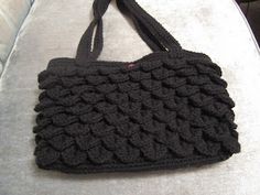 a black crocheted purse sitting on top of a couch