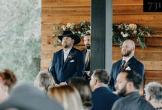 two men in suits are standing at the alter