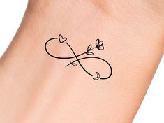 a small tattoo on the wrist of a woman's arm with an arrow and heart