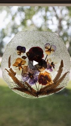 a glass vase with flowers in it sitting on top of a window sill next to a grass field