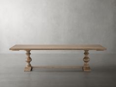 a wooden table sitting on top of a cement floor next to a white wall in an empty room