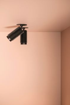 two hair dryers hanging from the ceiling in a room with pink walls and flooring