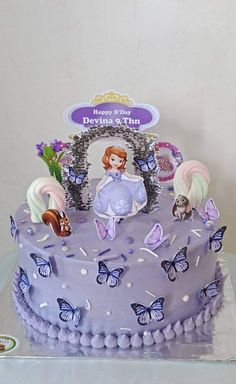 there is a purple cake with white frosting on the top and butterflies around it