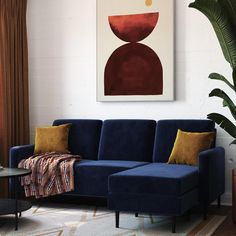 a living room with a blue couch and a painting on the wall above it,