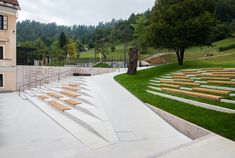 there are many wooden benches on the side of this building that is next to a park