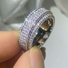 someone is holding a wedding ring that has three rows of diamonds on top of it