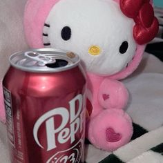 a hello kitty stuffed animal next to a coca - cola can