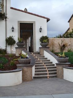 a white house with steps leading up to the front door and plants on either side