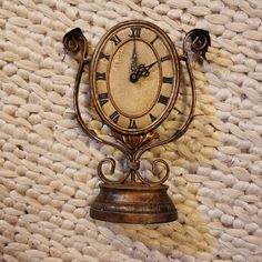 an old fashioned clock is sitting on the wall next to a knitted area rug