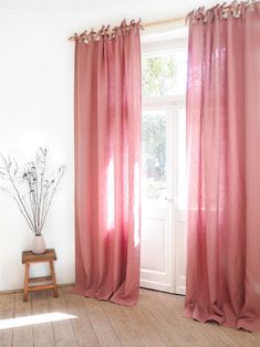 a room with a wooden floor and pink curtains