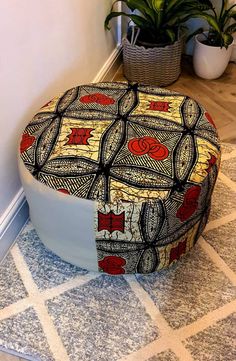 a round ottoman sitting on the floor next to a potted plant