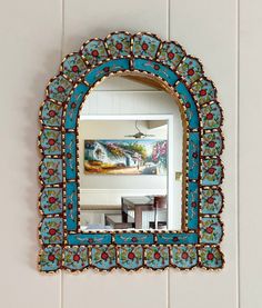 a blue mirror hanging on the wall above a sink in a room with white tile