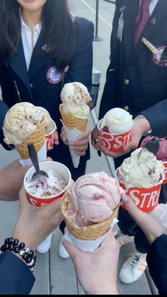 several people holding ice cream cones in their hands