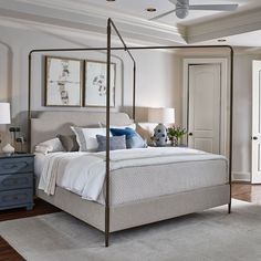 a bedroom with a four poster bed and blue nightstands on either side of the bed