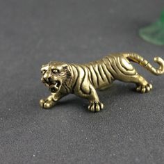 a small gold tiger figurine sitting on top of a black table next to a green vase