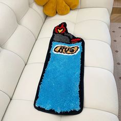 a stuffed animal sitting on top of a white couch next to a blue rug that says crayo