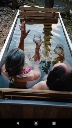 two people in a hot tub holding wine glasses