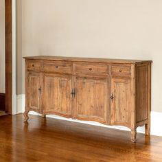 a large wooden cabinet sitting on top of a hard wood floored floor next to a white wall