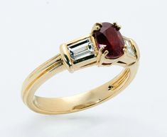 a yellow gold ring with an oval ruby and baguette diamond set in the center