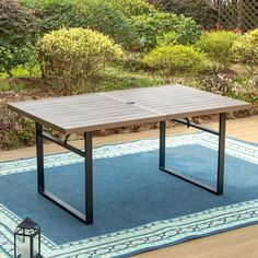 a ping pong table sitting on top of a blue rug in front of bushes