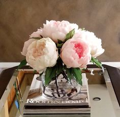 a glass vase filled with pink flowers sitting on top of a metal tray next to a mirror