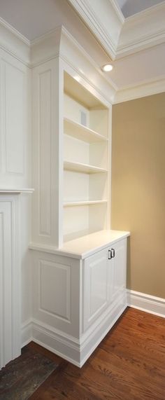 an empty room with white bookcases and wood floors