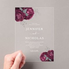 a person holding up a wedding card with purple flowers on the front and back side