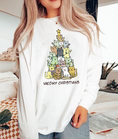 "Christmas Tree Shirt, Christmas Cat Shirt, Meowy Christmas Shirt, Christmas Cat Shirt, Retro Christmas Shirt, Merry Christmas Shirt 2023  Hi! Welcome to ThamDessignLTD.  We're thrilled to have you here!  At ThamDessignLTD, we offer a range of clean, high-quality, and soft shirts. Each item is carefully prepared by our boutique and undergoes thorough ironing before being shipped to you. We want you to have a seamless shopping experience and enjoy browsing through our collection. If you have any questions or need assistance, please don't hesitate to reach out to us. We're here to help you at any time. To ensure the perfect fit, we kindly request you to check our size cards before making your purchase. It will help you find the right size and ensure that you're completely satisfied with your White Long Sleeve T-shirt With Cat Design, White Cat Design Top For Winter, White Winter Top With Cat Design, Christmas Long Sleeve Tops With Cartoon Print, White Tops With Cartoon Print For Christmas, White Cat Print Top For Winter, White Cartoon Print Tops For Christmas, White Christmas Tops With Cartoon Print, White Christmas Cartoon Print Tops