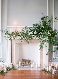 the fireplace is decorated with greenery and candles for an elegant touch to the room