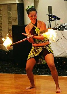 a woman is dancing with fire in her hand and holding a stick on the floor